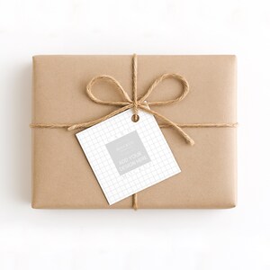 May include: A rectangular gift wrapped in brown paper, tied with twine, and a tag that says "ADD YOUR DESIGN HERE". The tag has a grid pattern and a grey square. The twine is tied in a bow.