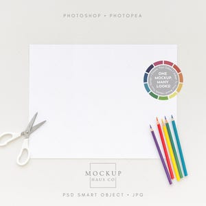 May include: A white paper sheet with scissors, colored pencils, and a color wheel graphic. The pencils are purple, red, yellow, green, and blue. The text on the color wheel says "ONE MOCKUP, MANY LOOKS!"