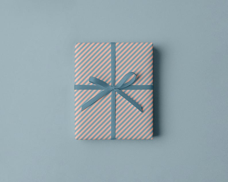 Puede incluir: Un regalo envuelto con un patr&oacute;n de rayas diagonales rosas y azules. El regalo est&aacute; atado con una cinta y un lazo azules. El fondo es azul claro.