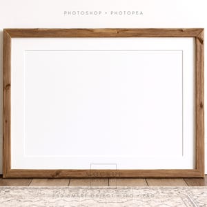 May include: A rectangular wooden picture frame with a white mat. The frame is made of a light brown, textured wood. The text "PHOTOSHOP • PHOTOPAE" is at the top. The frame is leaning against a white wall.