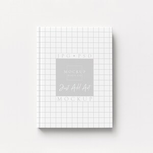 May include: A white notebook with a grid pattern on the cover. The notebook has the text "JPG PSD" at the top and "Mockup Daily Co" and "Just All Art Mockup" in a gray rectangle in the center.