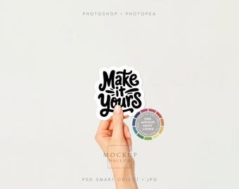 May include: A hand holding a white sticker with the phrase "Make it yours" in black script. A color wheel with the text "One Mockup Many Looks" is next to the sticker. The background is plain white.
