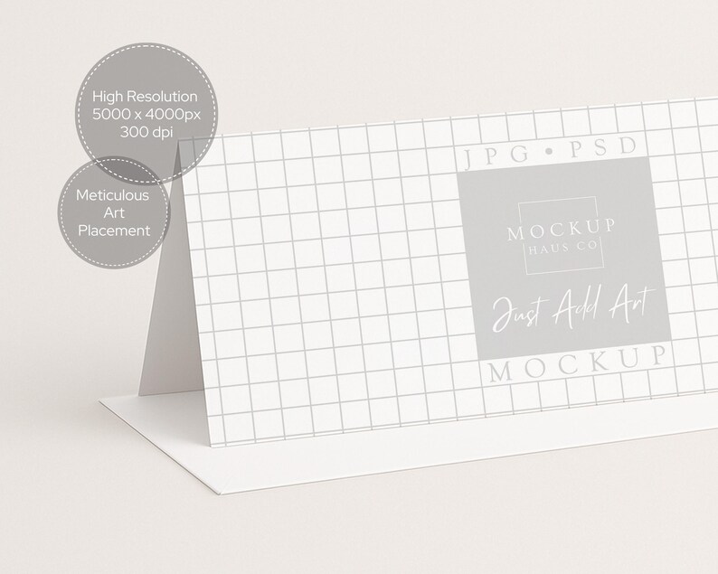 Pu&ograve; includere: Un mockup di biglietto bianco piegato con un motivo a griglia sul davanti. La carta presenta il testo "MOCKUP HAUS CO" e "Just Add Art". Il testo aggiuntivo include "High Resolution" e "Meticulous Art Placement".