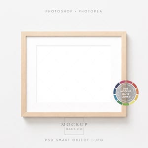 May include: A rectangular, light-colored wooden picture frame with a white mat. The frame is set against a white background. A color wheel graphic is in the lower right corner. Text at the top reads "PHOTOSHOP • PHOTOPEA".