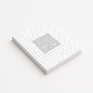 Peut inclure: Une pile de papier blanc avec un motif quadrill&eacute;, inclin&eacute;e sur une surface blanche. Un carr&eacute; gris avec le texte "ADD YOUR WORK HERE" est centr&eacute; sur le dessus. Les mots "JPG PSD" et "MOCKUP" sont &eacute;galement visibles.