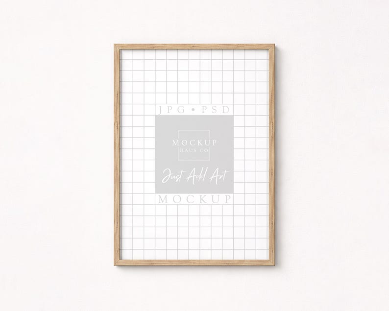 May include: A rectangular wooden picture frame with a grid pattern background. The frame has a light brown color and contains the text "JPG PSD", "MOCKUP HAUS CO", and "Just Add Art MOCKUP" in a light gray color.