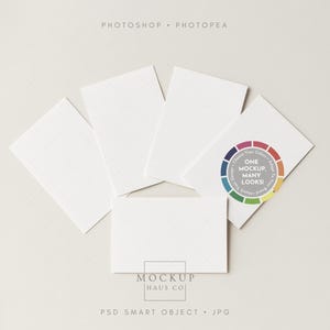 May include: A mockup featuring five white rectangular cards arranged on a light gray surface. The cards are blank, with a subtle grid pattern. A circular color wheel graphic with the text "ONE MOCKUP, MANY LOOKS!" is visible. The text "MOCKUP HAUS CO" is also present.