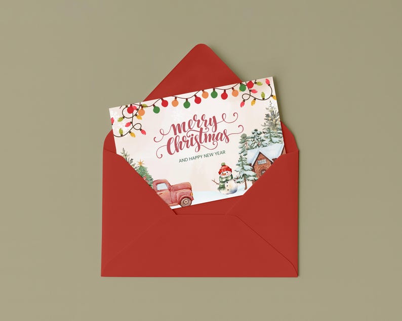 May include: A red envelope containing a Christmas card. The card features a watercolor illustration of a red truck, snowman, and a house in a snowy landscape. The card reads "Merry Christmas and Happy New Year" with festive string lights.