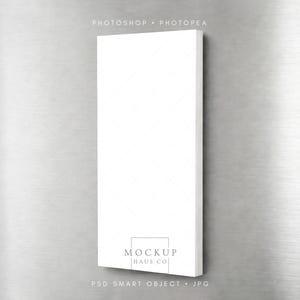 Puede incluir: Una maqueta de lienzo rectangular blanco con un sutil patrón de diamantes, sobre un fondo de metal cepillado. El lienzo presenta el texto "MOCKUP HAUS CO" y "PSD SMART OBJECT • JPG". La parte superior de la imagen dice "PHOTOSHOP • PHOTOPEA".