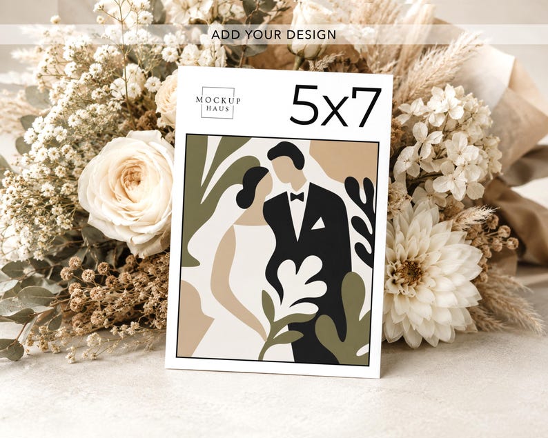 Pu&ograve; includere: Un biglietto di nozze di 12,7 x 17,8 cm con un'illustrazione astratta di una sposa e uno sposo, circondati da forme verde oliva e beige. Il biglietto &egrave; esposto davanti a un bouquet di fiori bianchi e beige.