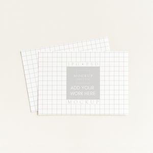 K&ouml;nnte beinhalten: Zwei wei&szlig;e rechteckige Karten mit einem Rastermuster, eine &uuml;berlappt die andere leicht. Die Karten tragen den Text "JPG &bull; PSD" und "MOCKUP" mit den Worten "ADD YOUR WORK HERE" in der Mitte.