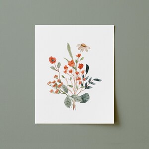 May include: Watercolor painting of a floral arrangement featuring orange and red flowers, green leaves, and a single daisy. The artwork is on a white background, with a soft, natural aesthetic. The painting is centered on a white rectangular paper.
