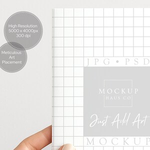 May include: A white notebook with a grid pattern, featuring the text "MOCKUP HAUS CO" and "Just Add Art." The image also includes text indicating high resolution and meticulous art placement, ideal for digital art mockups.
