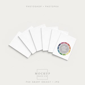 May include: A fan of white rectangular cards, one with a colourful circular design and the text "ONE MOCKUP MANY LOOKS!". The image also includes the text "PHOTOSHOP • PHOTOPEA" and "MOCKUP HAUS CO".