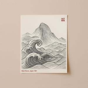 May include: A black and white print featuring a mountain and ocean waves. The artwork has a minimalist style with detailed line work. The text "Mani Store, Japan 1961" is printed at the bottom. Red Japanese characters are at the top.