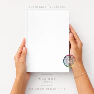 May include: A white book with a textured cover is held by two hands against a white background. The book has a subtle diamond pattern. The image includes the text "PHOTOSHOP • PHOTOPEA" and "MOCKUP HAUS CO". A color palette is also visible.