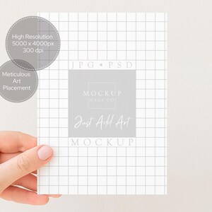 Peut inclure: Une maquette de carte blanche avec un motif quadrill&eacute;, tenue par une main. La carte contient le texte &laquo; Just Add Art &raquo; et &laquo; Mockup Haus Co. &raquo; ainsi que des d&eacute;tails sur la r&eacute;solution de l'image et le placement de l'art.