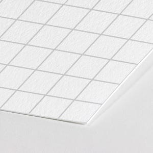 May include: A sheet of white paper with a light gray grid pattern printed on the surface. The paper has a textured finish and is positioned at an angle, showing a sharp corner and straight edges against a plain white background.
