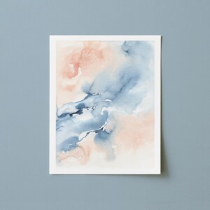 May include: Watercolor painting on white paper featuring abstract shapes in shades of blue and peach. The artwork has a soft, blended appearance, with the colors merging and flowing together. The painting is displayed against a light blue background.