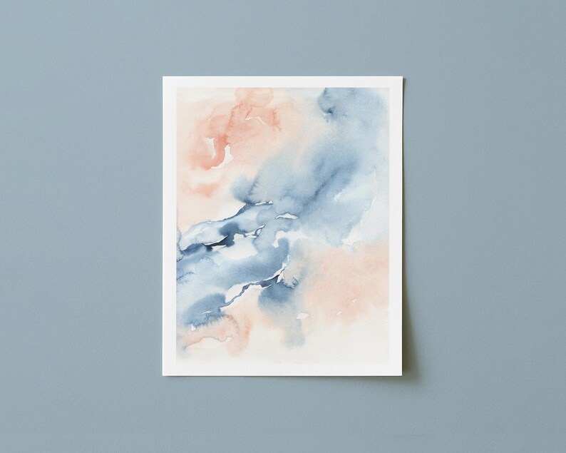 May include: Watercolor painting on white paper featuring abstract shapes in shades of blue and peach. The artwork has a soft, blended appearance, with the colors merging and flowing together. The painting is displayed against a light blue background.