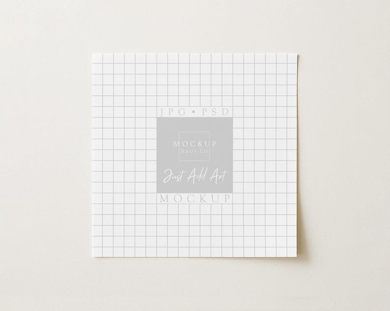 May include: Square white paper with a grid pattern, featuring the text "JPG PSD" at the top and "MOCKUP HAUS CO" and "Just Add Art MOCKUP" in a central gray square. The paper is on a light beige surface.