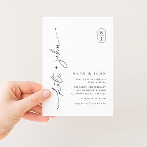 Peut inclure: Une invitation de mariage blanche avec une &eacute;criture noire. Le texte indique "Kate + John" en cursive, avec des d&eacute;tails tels que la date, l'heure et le lieu du mariage. Un monogramme avec les lettres "K" et "J" est dans le coin sup&eacute;rieur droit.