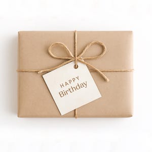 May include: A rectangular gift wrapped in brown paper, tied with twine, and decorated with a twine bow. A cream-coloured tag with the words "HAPPY Birthday" is attached to the bow.