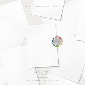 May include: An assortment of white rectangular papers with a subtle grid pattern, scattered on a light grey background. The image features the text "Photoshop • Photopea" and "Mockup Haus Co." with "PSD Smart Object • JPG". A circular colour wheel graphic is also visible.