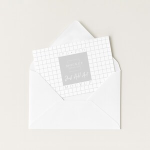May include: A white envelope with a card inside. The card has a grid pattern and the text "JPG PSD MOCKUP MAKER Just All Art MOCKUP" in a gray square. The envelope is open, revealing the card.