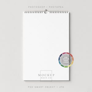以下が含まれることがあります： 白いリング綴じのノートで、円形のカラーパレットグラフィックと「ONE MOCKUP MANY LOOKS」の文字が入っています。 ノートは金属製のスパイラルから吊り下げられており、上部には「PHOTOSHOP • PHOTOPEA」の文字があります。