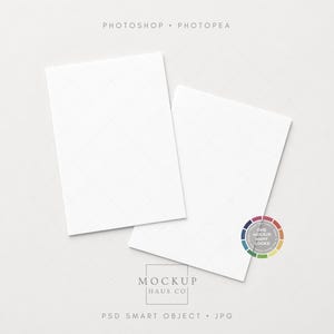 May include: Two white rectangular cards with a subtle diamond pattern, slightly overlapping on a light gray surface. The cards are positioned at an angle, with text at the top and bottom, and a color wheel graphic on the right.