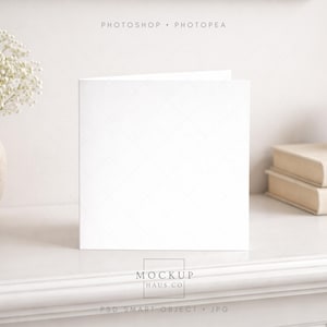 May include: A white square card, slightly open, sits on a white surface. A vase of white flowers is on the left, with books and a small cup on the right. The text "PHOTOSHOP • PHOTOPEA" is at the top. The card is a mockup.