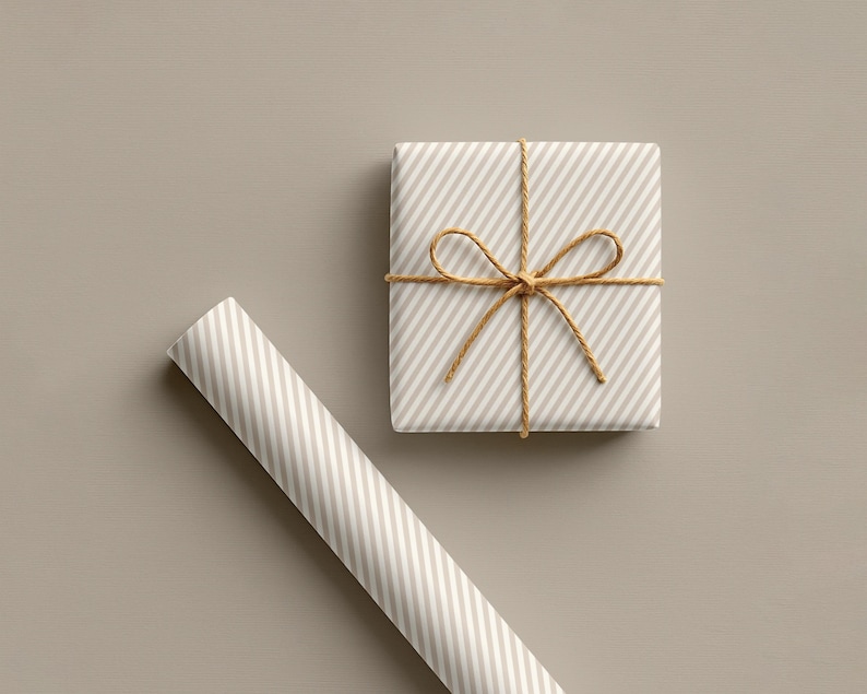 May include: A wrapped gift box and a roll of wrapping paper. Both are light beige with diagonal white stripes. The gift is tied with twine in a bow. The background is a solid light beige colour.