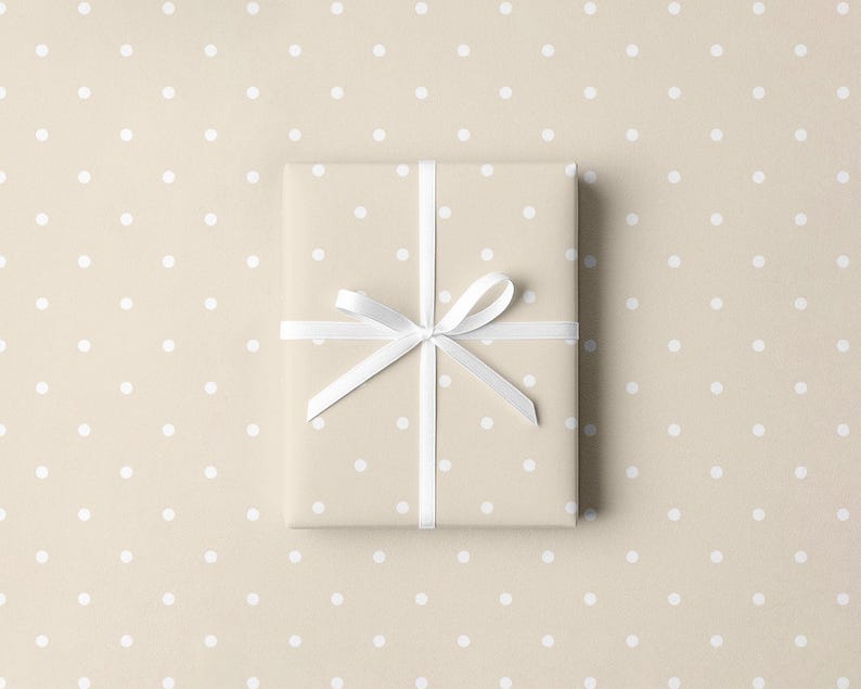 May include: A wrapped gift box with a white ribbon and bow, presented on a beige background with white polka dots. The wrapping paper has a similar polka dot pattern.
