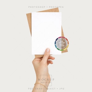 May include: A white card and a brown envelope are held in a hand. The card is blank, and the envelope is slightly visible behind it. A color wheel with the text "ONE MOCKUP MANY LOOKS" is in the image. The words "MOCKUP HAUS CO" are also visible.