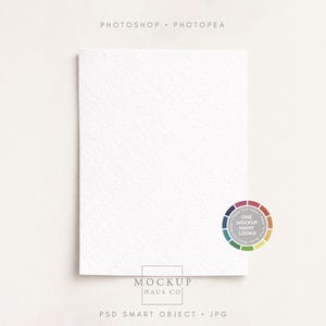 以下が含まれることがあります： 丸みを帯びた角を持つ白いテクスチャ加工された紙のカードで、柔らかな白い背景に配置されています。カードには、微妙なエンボス加工のパターンがあります。画像には、PHOTOSHOP、PHOTOPAE、MOCKUP HAUS CO、PSD SMART OBJECT、JPGというテキストとカラーホイールが含まれています。