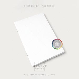 May include: A white notebook with a subtle grid pattern on the cover. The image includes text that reads "Photoshop Photopea" and "Mockup Haus Co." A colour wheel graphic is also present, with the text "One Mockup Many Looks."