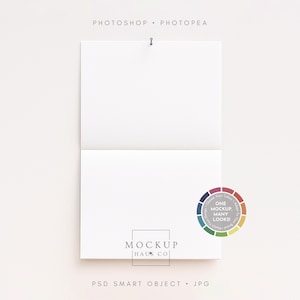 Könnte beinhalten: Ein weißes, offenes Notizbuch-Mockup mit einer silbernen Nadel oben. Der Text "PHOTOSHOP • PHOTOPEA" befindet sich über dem Notizbuch. Der untere Teil des Notizbuchs trägt den Text "MOCKUP HAUS CO" und "PSD SMART OBJECT • JPG". Rechts befindet sich ein Farbrad.