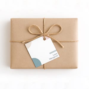 May include: A rectangular gift wrapped in brown paper, tied with twine, and a tag. The tag has a design with beige, blue, and pink accents, and the text "Love, Margaret".