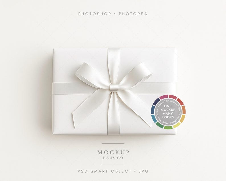 May include: A white rectangular gift box tied with a satin ribbon and bow. The box is wrapped in white paper. A circular graphic with the text "ONE MOCKUP, MANY LOOKS!" is on the right. The text "MOCKUP HAUS CO" is at the bottom.