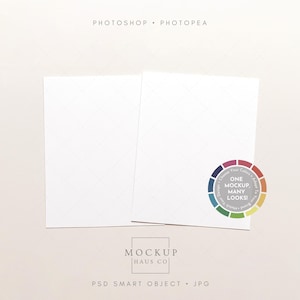 May include: Two white rectangular cards with a subtle diamond pattern, presented on a light beige background. A colorful circular graphic with the text "ONE MOCKUP, MANY LOOKS!" is on the right. The text "MOCKUP HAUS CO" is at the bottom.