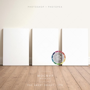 Op de afbeelding: Drie blanco witte canvas panelen tegen een crèmekleurige muur op een houten vloer. De tekst "PHOTOSHOP • PHOTPEA" staat bovenaan en een kleurenwielafbeelding staat in het midden. De onderste tekst luidt "MOCKUP INAUS CO" en "PSD SMART OBJECT • JPG".