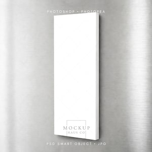 Puede incluir: Un lienzo rectangular blanco con un sutil patrón de diamantes, fijado a una superficie de metal cepillado. El lienzo presenta el texto "MOCKUP HAUS CO" y "PSD SMART OBJECT . JPG".