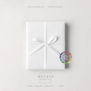 Puede incluir: Una caja de regalo blanca envuelta en papel blanco y atada con una cinta de raso blanca. La imagen incluye el texto "PHOTOSHOP &bull; PHOTOPAE" y "MOCKUP HAUS CO". Tambi&eacute;n se incluye una rueda de color con el texto "ONE MOCKUP MANY LOOKS".