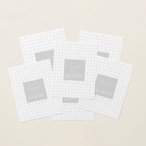 May include: Several white square papers with a grid pattern, arranged on a pale beige surface. Each paper features a grey square with the text "Mockup" and "Just Add Art". The papers overlap, creating a layered effect.