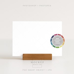 May include: A white rectangular card is held by a rectangular wooden holder. A color wheel graphic with the text "ONE MOCKUP. MANY LOOKS!" is on the right. The text "MOCKUP HAUS CO" and "PSD SMART OBJECT . JPG" are at the bottom.