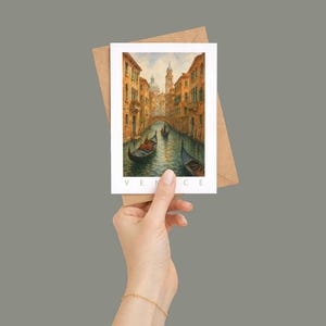 May include: A watercolor postcard featuring a Venetian canal scene with gondolas, buildings, and a bridge. The postcard is held with a brown envelope. The word "VENICE" is printed at the bottom of the postcard.