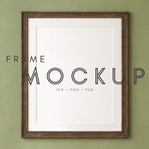 May include: A rectangular brown wooden frame with a white mat and a blank white space in the center. The words "FRAME MOCKUP" are printed in black, along with "JPG • PNG • PSD". The background is a textured olive green.