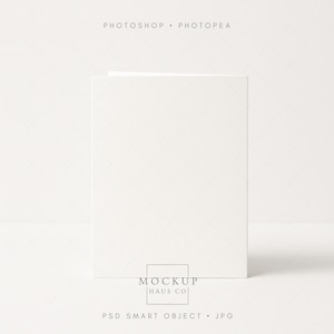 May include: A white, vertical greeting card mockup. The card is centered and stands upright against a white background. The text "PHOTOSHOP • PHOTOPEA" is at the top, and "MOCKUP HAUS CO" is at the bottom, along with "PSD SMART OBJECT • JPG".