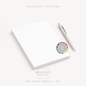 May include: A stack of white paper with a silver pen and a colorful circle graphic. The text "Photoshop Photopae" is at the top, and "Mockup Haus Co" is at the bottom. The graphic says "One Mockup Many Looks".